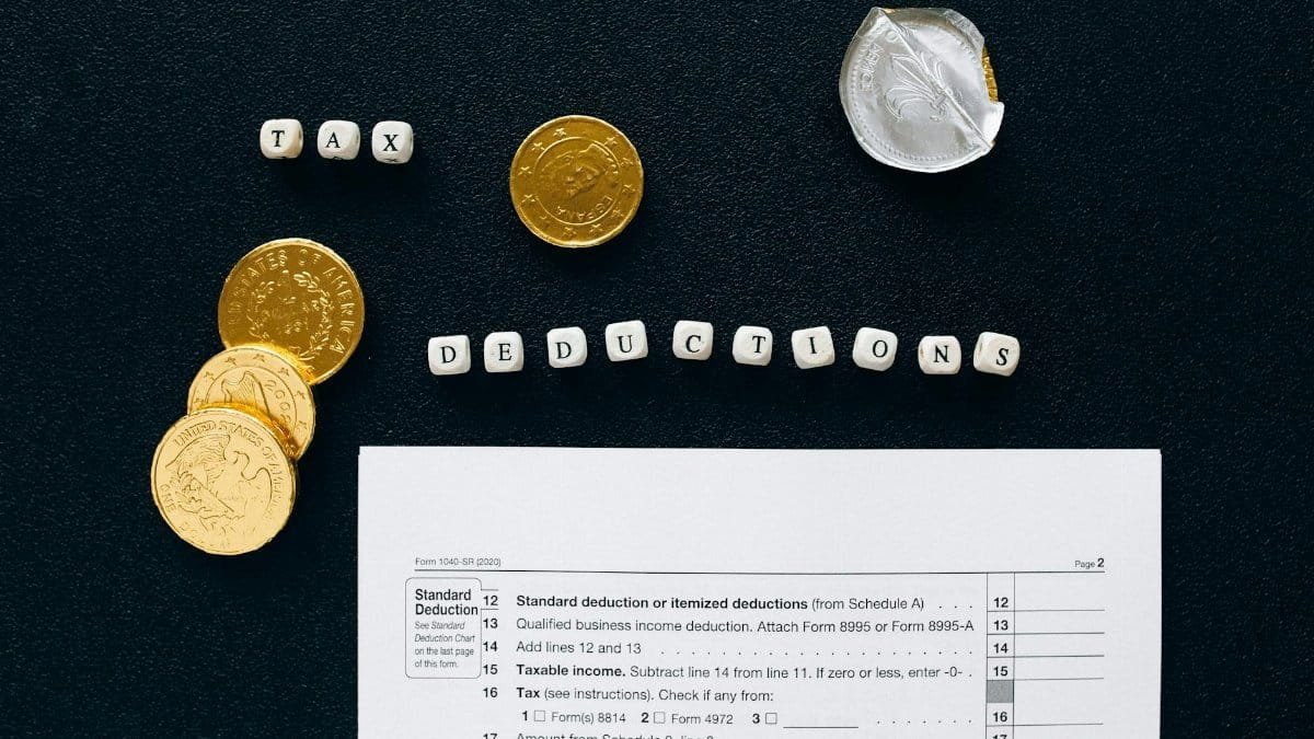 Image of tax deductions concept with coins and tax form on black background.