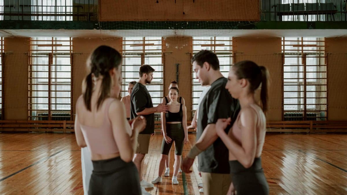 A group of people practicing and training in a gym setting, focusing on teamwork and coordination.