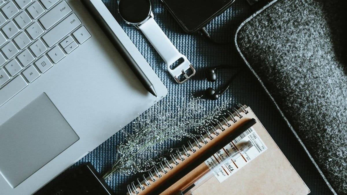 Flatlay of a modern workspace with a laptop, smartwatch, notebook, and tech gadgets, ideal for tech-themed projects.