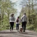 A family enjoying a walk with their dog on a picturesque forest path in spring.