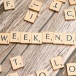 Wooden Scrabble tiles spelling 'weekend' on a rustic wooden table.