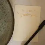 A note in Portuguese showing gratitude, accompanied by a pen and plate, on a table.