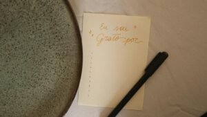 A note in Portuguese showing gratitude, accompanied by a pen and plate, on a table.