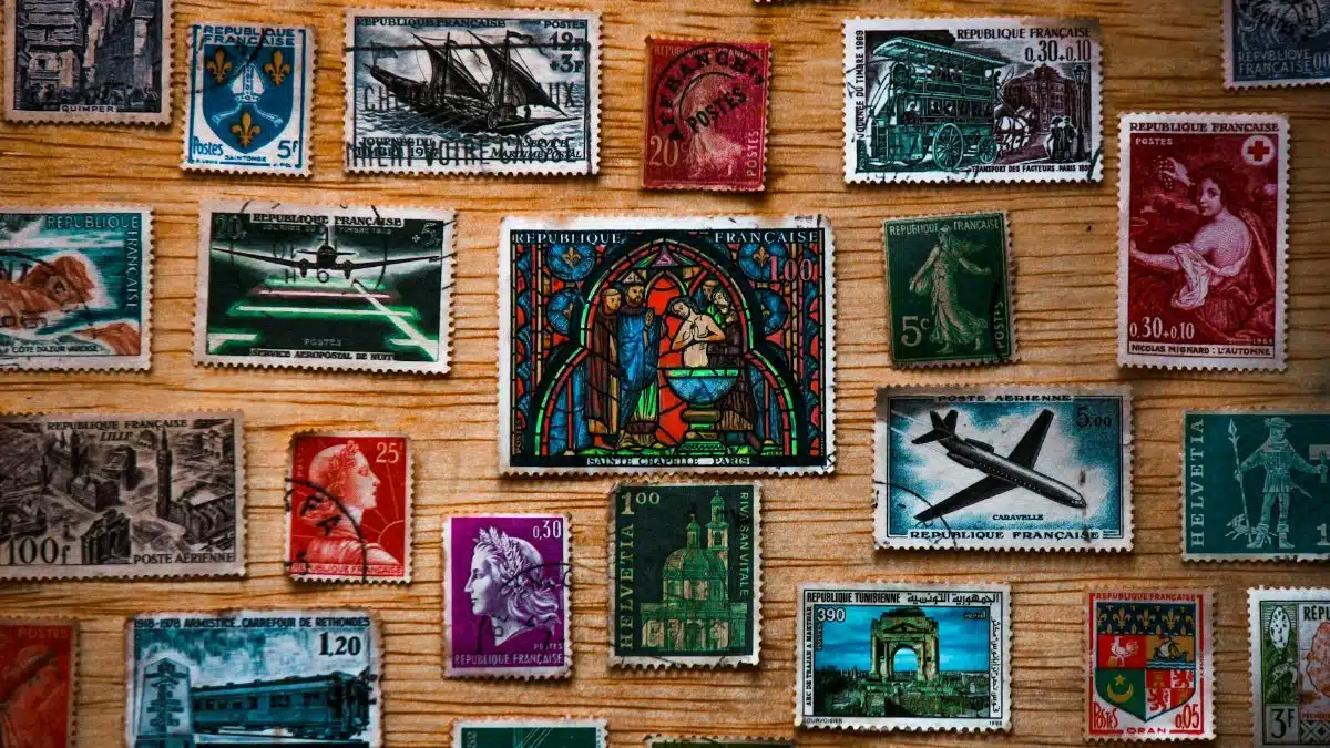 A collection of diverse vintage French postage stamps arranged on a wooden surface, showcasing history and art.