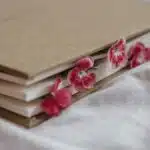 Agenda with hardcover and bright flowers with gentle petals between pages on creased textile