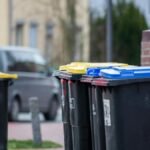 Color-coded trash bins on a city street in Gütersloh, Germany, showcasing urban waste management.