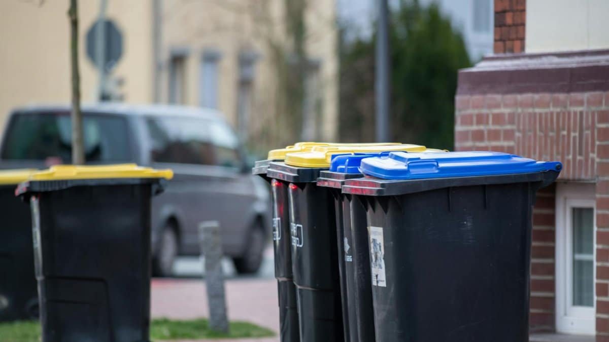 Color-coded trash bins on a city street in Gütersloh, Germany, showcasing urban waste management.