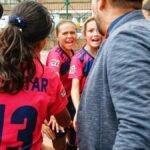 A vibrant moment capturing a youth soccer team in a motivational huddle with their coach, outdoors.