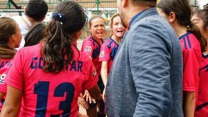 A vibrant moment capturing a youth soccer team in a motivational huddle with their coach, outdoors.