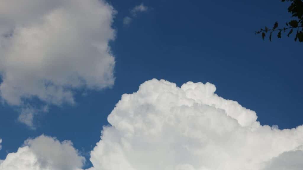 Fluffy white cumulus clouds in a deep blue sky, capturing serene summer weather.