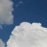 Fluffy white cumulus clouds in a deep blue sky, capturing serene summer weather.