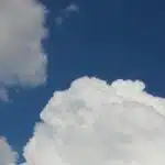 Fluffy white cumulus clouds in a deep blue sky, capturing serene summer weather.