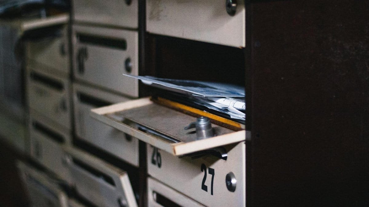 Close-up of an open mailbox in a residential building with visible mail, showcasing selective focus.