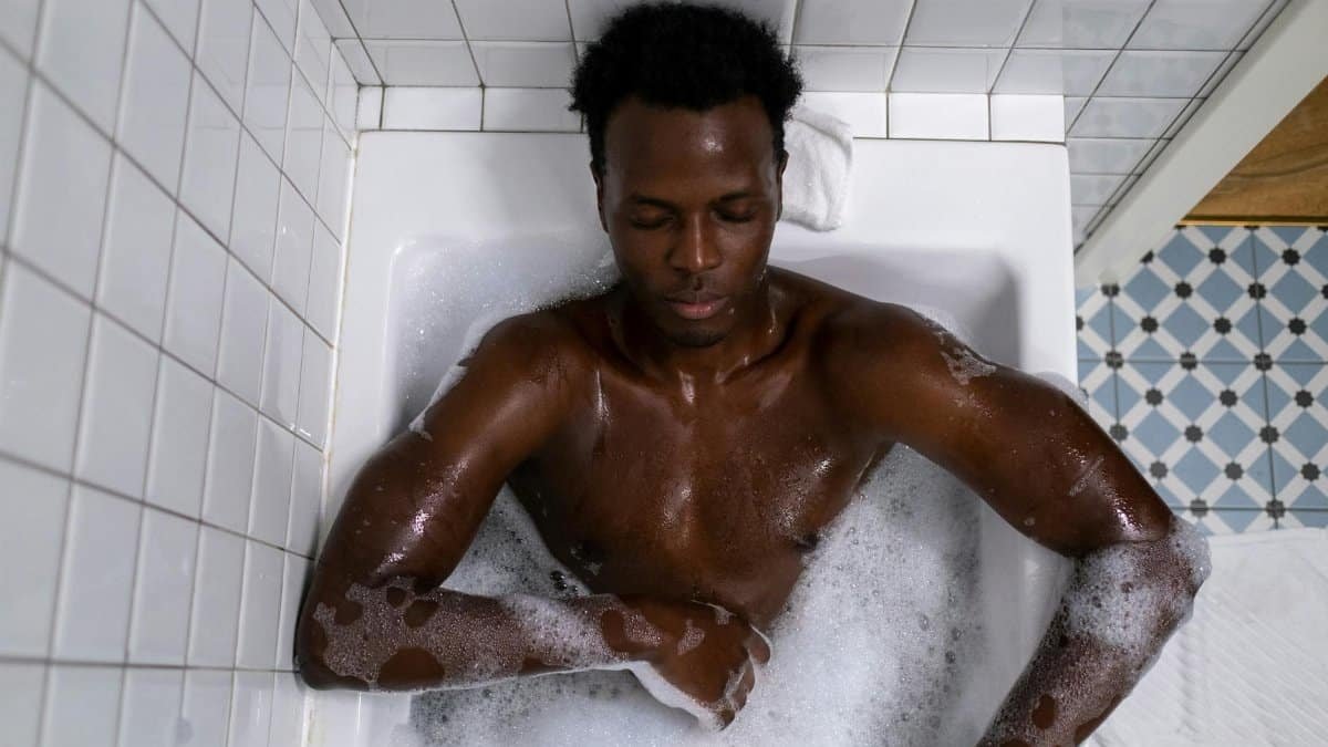 A man relaxing in a bathtub filled with bubbles, enjoying a calming bath experience indoors.