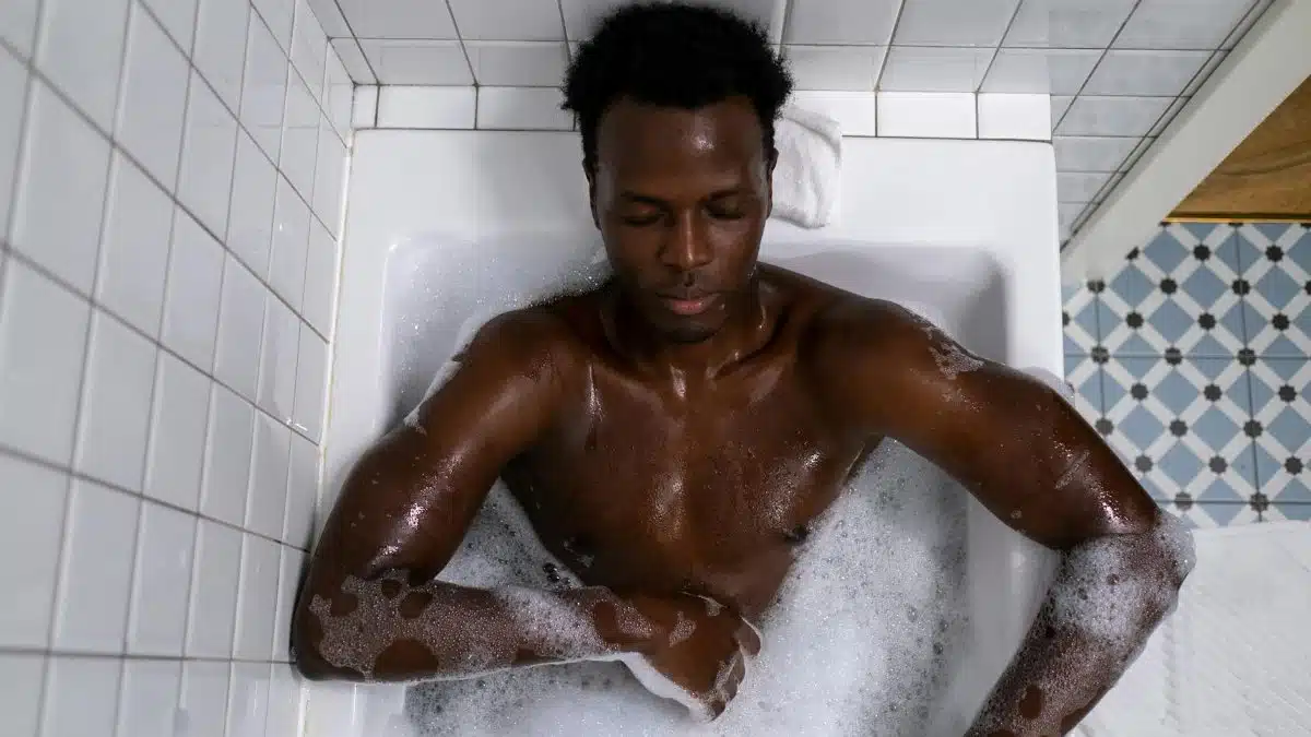 A man relaxing in a bathtub filled with bubbles, enjoying a calming bath experience indoors.