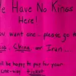 A vibrant protest sign in South Kingstown, Rhode Island, advocating against monarchies with political messaging.