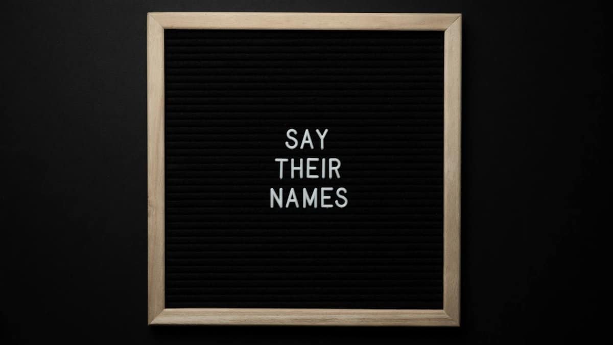 Top view composition of black framed photo with white text Say Their Names placed on black background