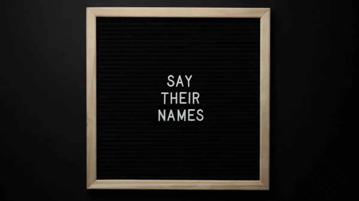 Top view composition of black framed photo with white text Say Their Names placed on black background