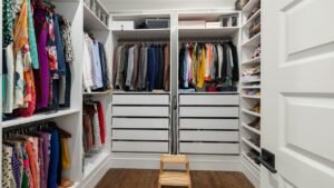 A neatly arranged walk-in closet showcasing a colorful variety of clothes and shoes.
