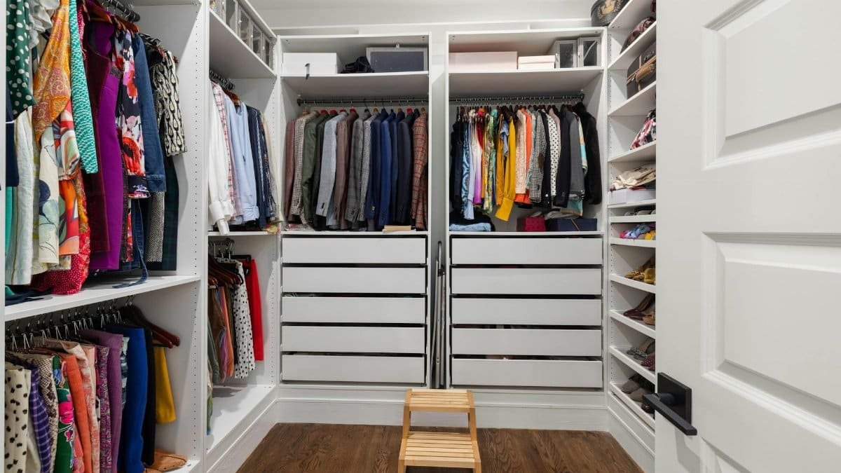 A neatly arranged walk-in closet showcasing a colorful variety of clothes and shoes.