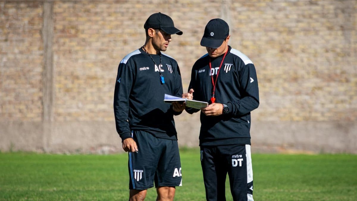 Two soccer coaches reviewing strategies on the field during the day.