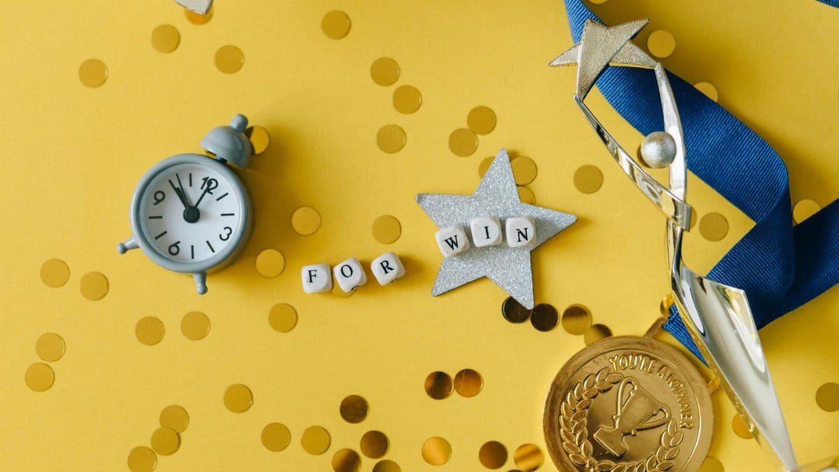 Conceptual flat lay of a trophy, medal, and clock with 'FOR WIN' letters, symbolizing victory and achievement.