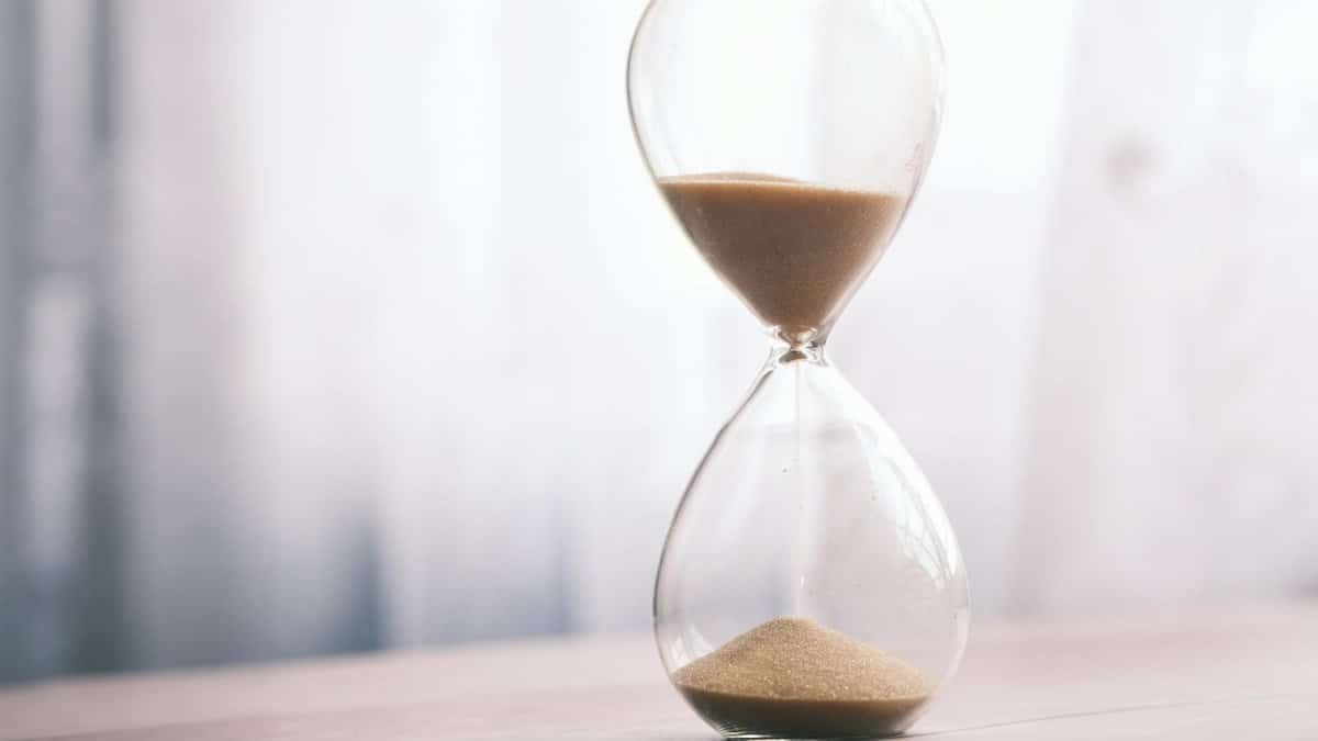 Minimalist hourglass filled with sand symbolizing time and patience, against a soft background.