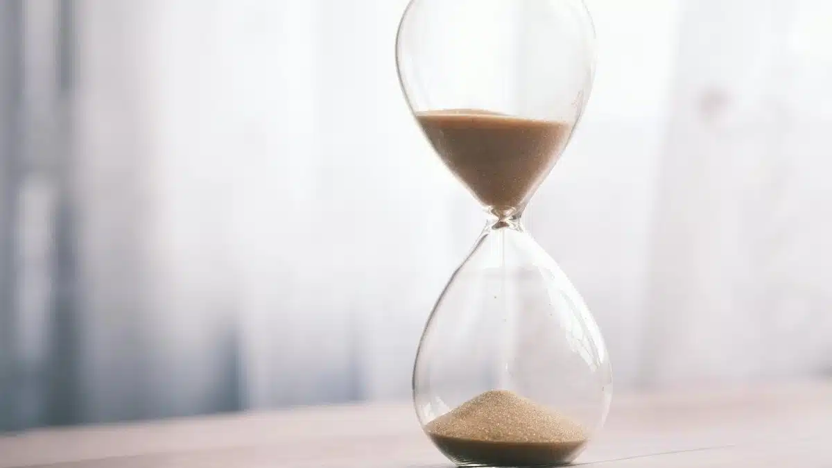 Minimalist hourglass filled with sand symbolizing time and patience, against a soft background.