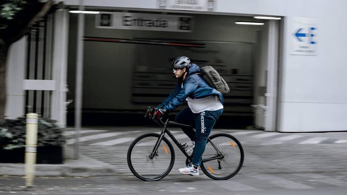 A man rides a bicycle quickly through a modern city street, showcasing urban mobility.