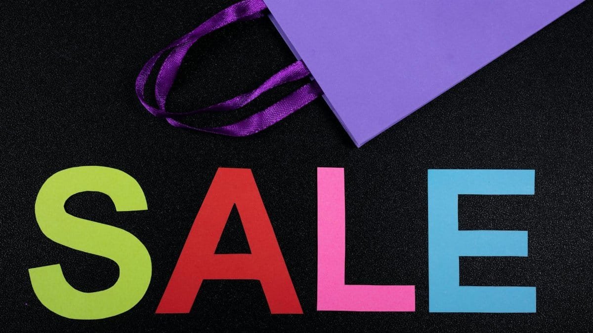Brightly colored letters spelling sale with a purple paper bag on black background.