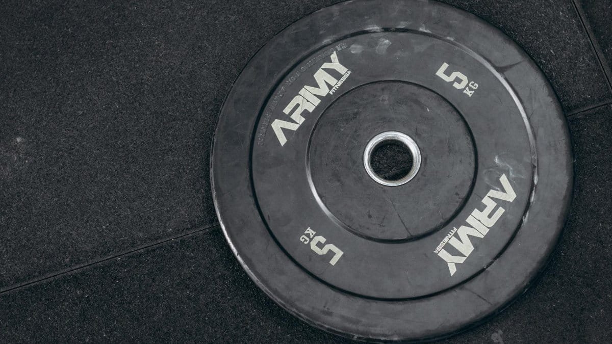 Black 5kg weight plate on gym floor, perfect for strength and fitness themes.