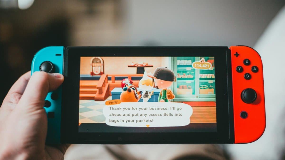 Crop anonymous person playing videogame while using game console and sitting at home on blurred background