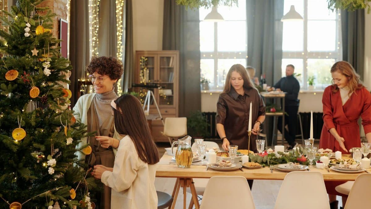 Festive family gathering decorating a Christmas tree and preparing a holiday meal indoors.