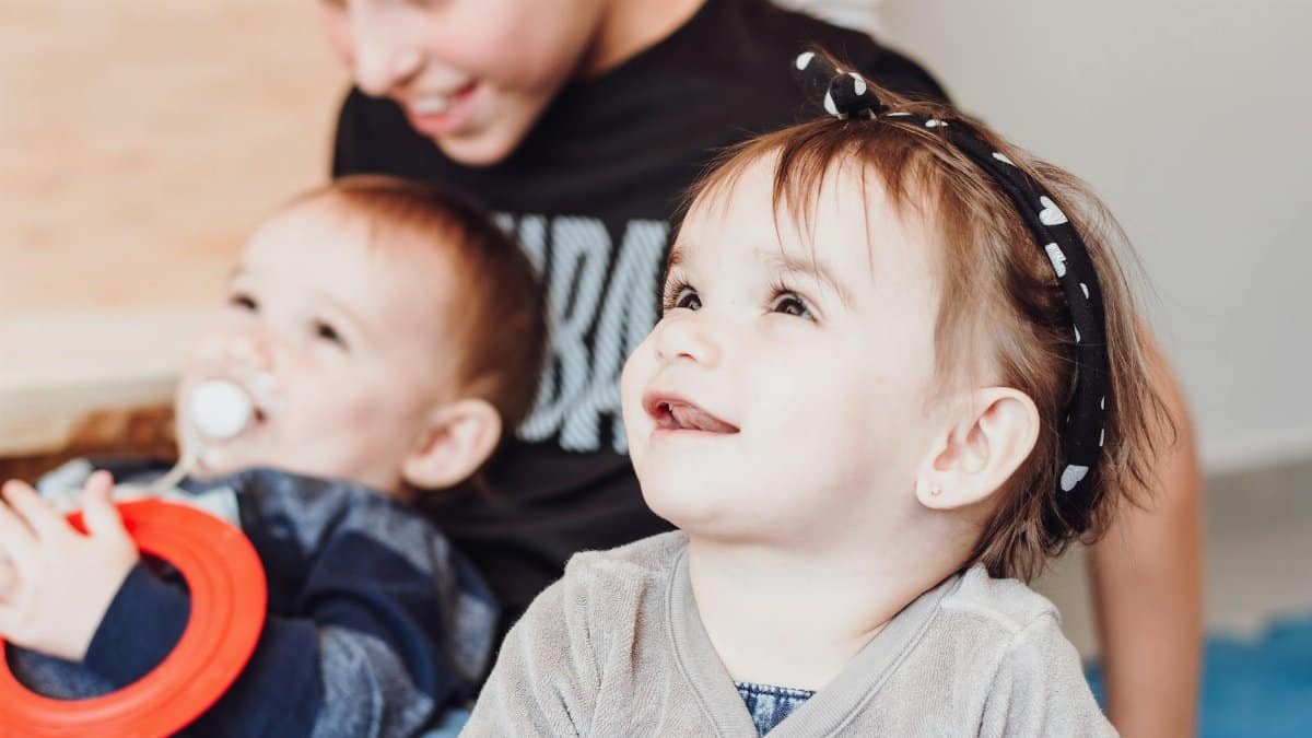 Joyful toddlers and sibling playing indoors, capturing love and innocence.