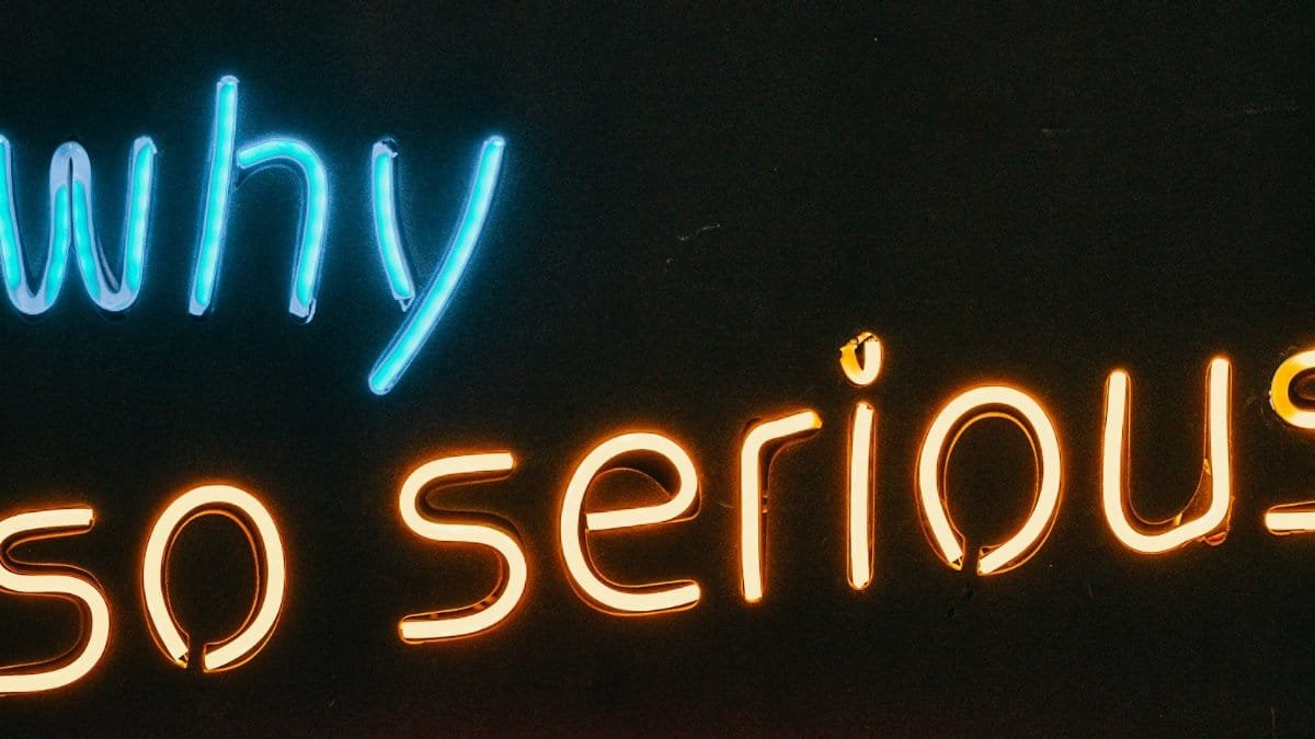 Vibrant neon sign displaying 'Why So Serious' text against a dark background.